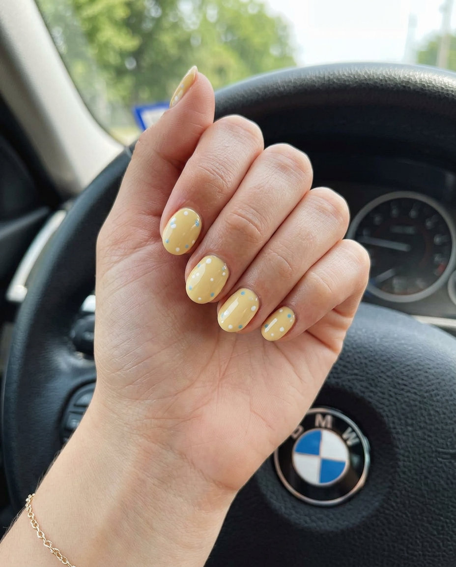 Short oval summer gel nails with muted butter yellow dots on sheer natural base, dainty for picnics 2026.