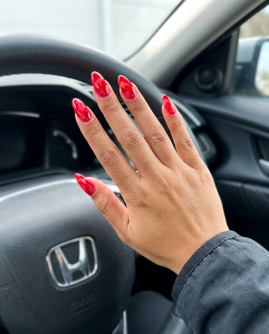 Abstract Jelly Cherry Swirl nails for summer 2026. Whimsical festival nails with translucent red swirls.