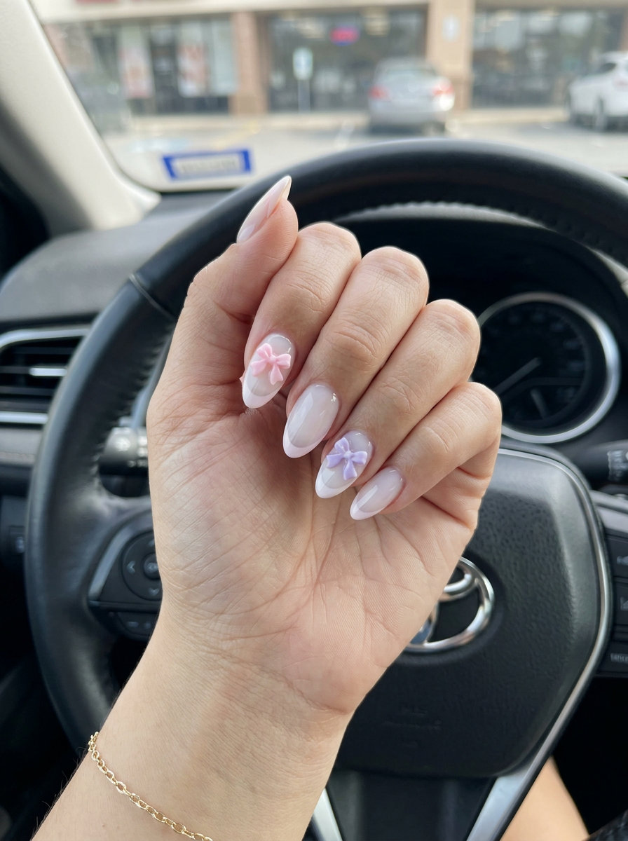 Milky almond French nails with 3D bows for weddings and date nights, a whimsical trending summer nails 2026 choice.